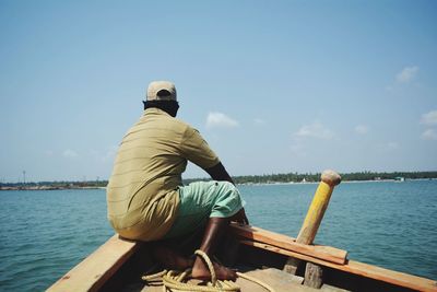 Rear view of man on boat in sea against sky