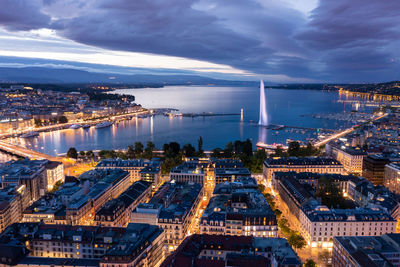 High angle view of illuminated city buildings against sky at dusk