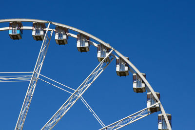 Low angle view of ferris wheel against clear blue sky