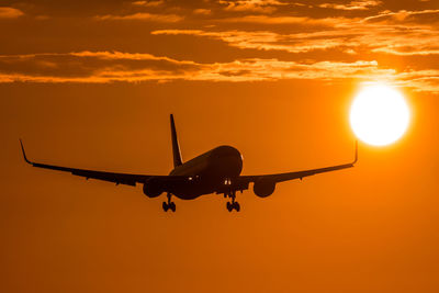 Airplane flying in sky during sunset