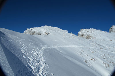 Scenic view of snowcapped mountains against clear blue sky