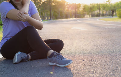 Low section of woman sitting on road