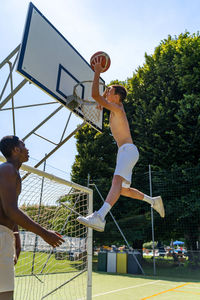 Young caucasian basketball player athlete in action jumping on artificial turf playing field