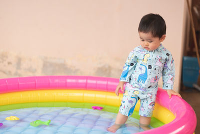 Cute baby girl standing in inflatable swimming pool