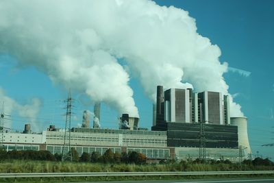 Smoke emitting from factory against sky