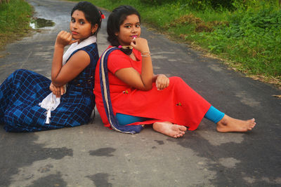 Portrait of friends sitting on road in city