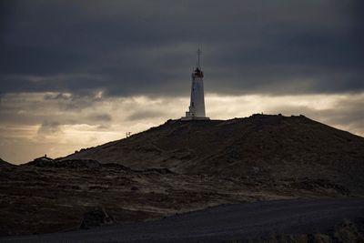 Low angle view of lighthouse by building against sky