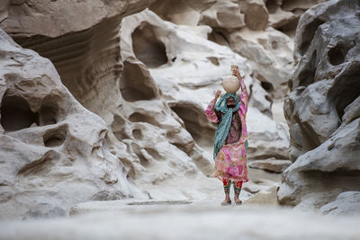 Rear view of woman walking near rock formations