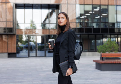 Portrait of young woman standing in city