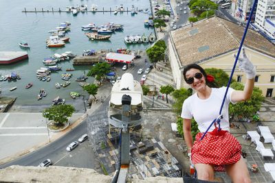 Caucasian woman wearing hero costume descending a tall building in rappel. 