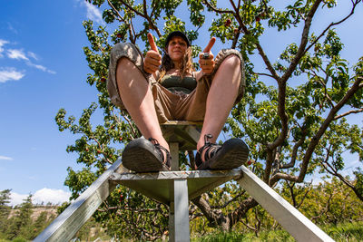 Low angle view of man sitting against sky