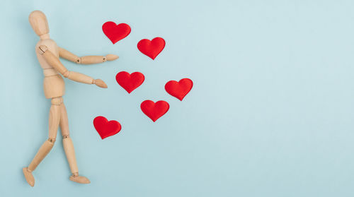 Cropped hand of woman holding heart shape against blue background