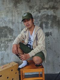 Portrait of young man standing against wall