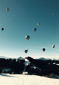 Hot air balloons flying over landscape against sky