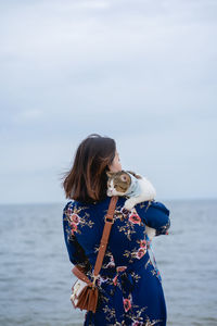 Woman relax sit on beach chair and hug her cat on sand beach