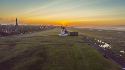 Rear view of man on field against sky during sunset