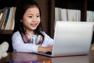 Close-up of girl using laptop while sitting at desk