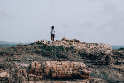 Full length of woman standing on rock against sky