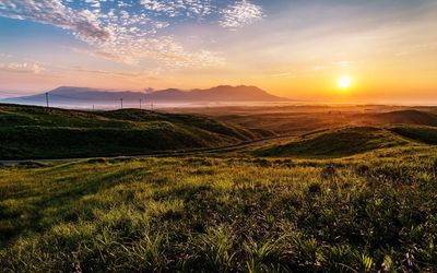 Idyllic shot of green landscape against sky during sunset