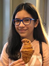 Portrait of smiling teenage girl holding croissant