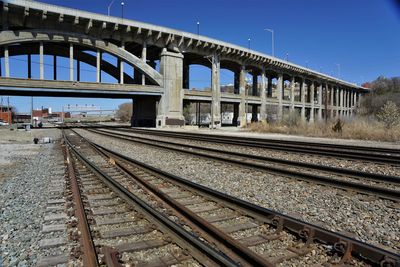 Railroad tracks against overpass and clear sky