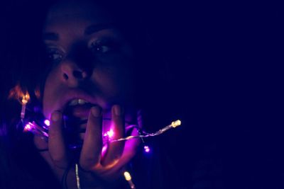 Portrait of woman holding illuminated lighting equipment at night