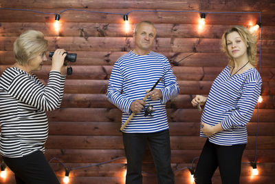 Woman looking through binoculars at couple holding fishing rod