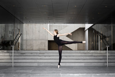 Ballerina in black leotard in modern concrete building