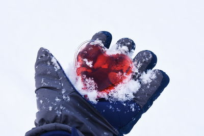 Cropped hand holding heart shape and snow during winter