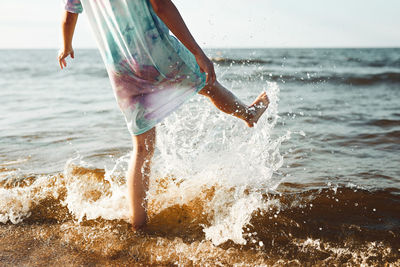 Midsection of woman splashing water at beach