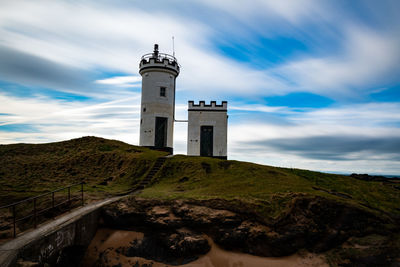 Low angle view of lighthouse amidst buildings against sky