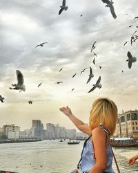 Rear view of seagulls flying over city against sky