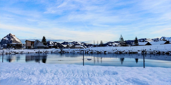 Snow covered houses by building against sky