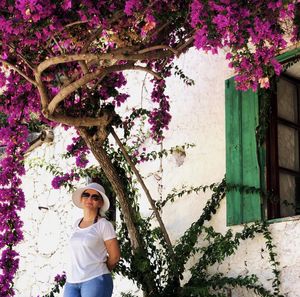 Portrait of woman standing by purple flowering tree