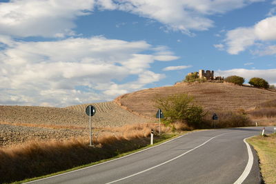 Country road by landscape against sky