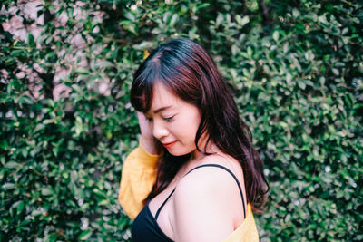 Close up of young pretty asian woman in blue yellow sweater with garden background.