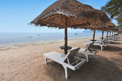 Deck chairs on beach against clear sky