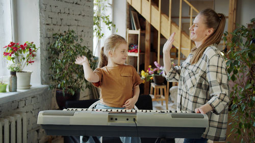 Mother and daughter doing high five by piano