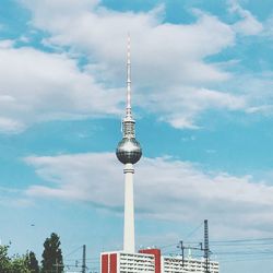 Low angle view of communications tower against cloudy sky