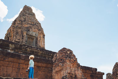 Rear view of woman standing against old building