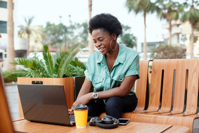 Smiling young woman using laptop on table at cafe