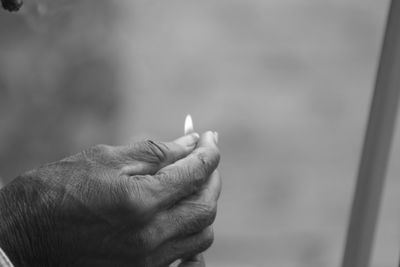 Close-up of hand holding lit match stick