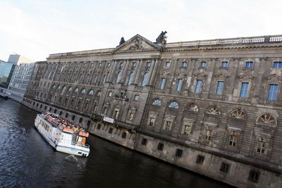 Tilt image of ferry boat in river by building