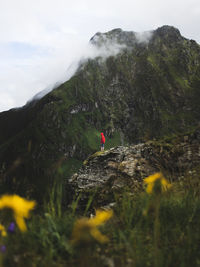 Person on rock by land against mountains