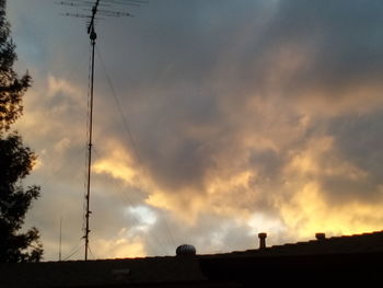 Low angle view of power lines against cloudy sky