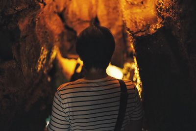 Rear view of man standing in illuminated cave