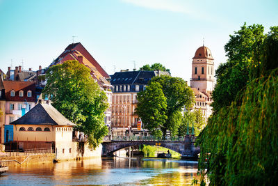 Bridge over river amidst buildings in city against sky