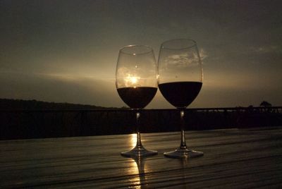 Close-up of wineglass against sky during sunset