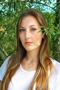 Portrait of beautiful young woman against plants