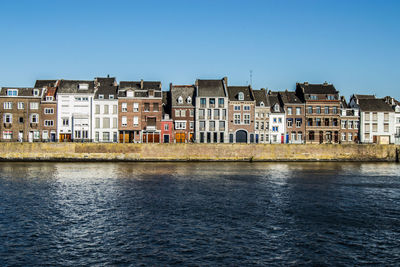 River by residential buildings against clear sky